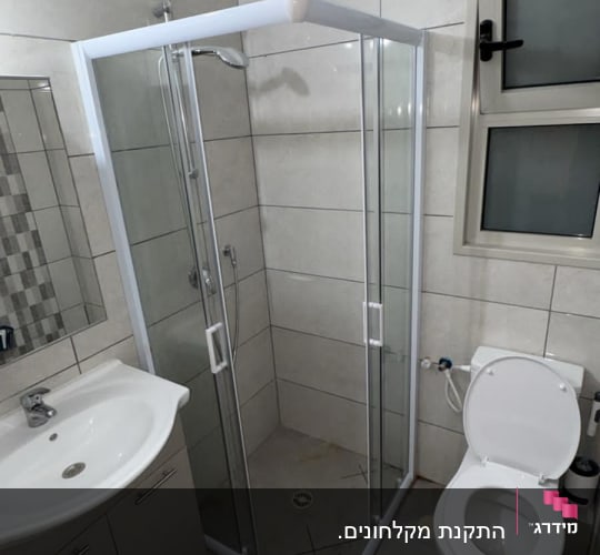 התקנת מקלחון פינתי בעל דלתות הזזה ומסגרת לבנה בחדר רחצה